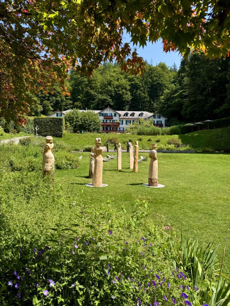 Garden with wooden sculptures and flowers at Grand Hotel Giessbach near Lake Brienz