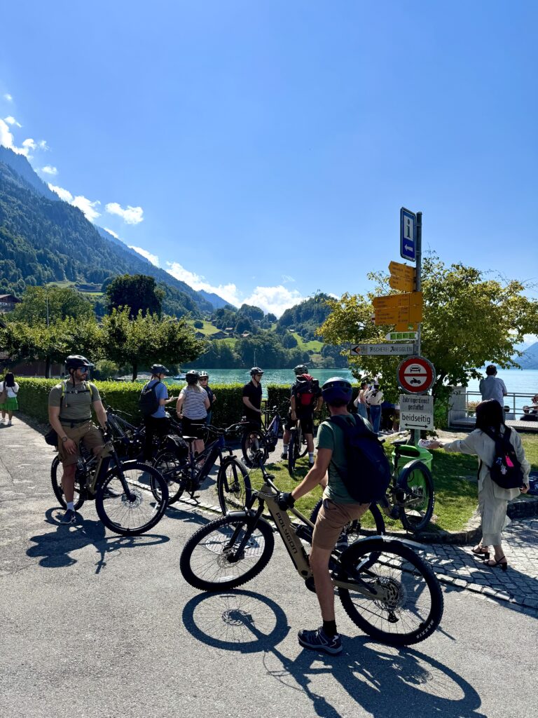 Cyclists taking a break by the turquoise shores of Lake Brienz during an e-bike tour from Interlaken