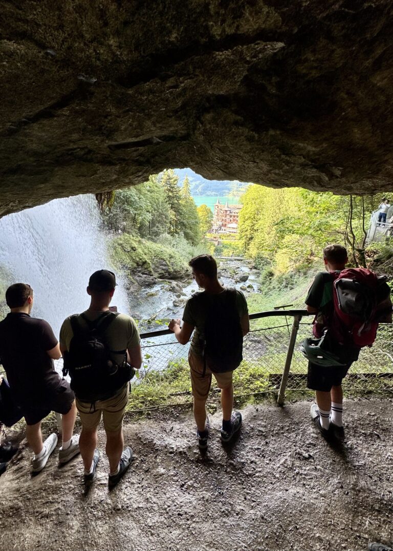 Visitors standing on the rocks beneath Giessbach Waterfalls near Lake Brienz