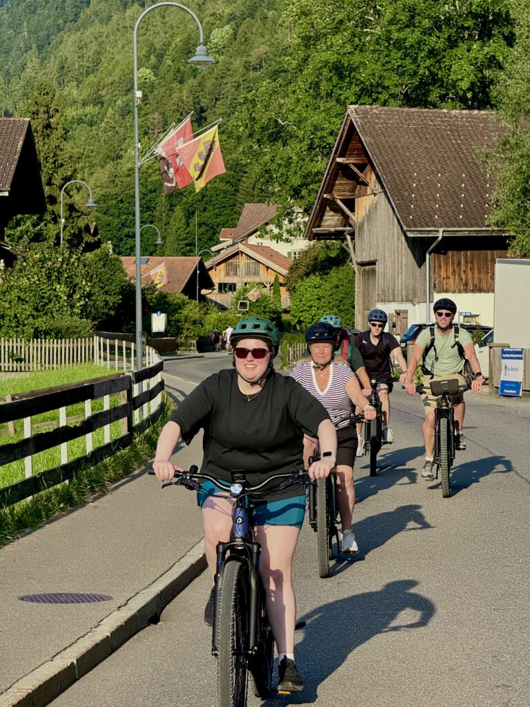 Cyclists riding through Swiss village on Interlaken E-bike Tour